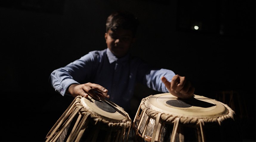 Students performing music with guitar and tabla at an ABSKM event